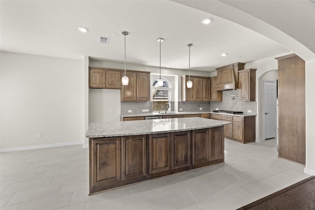 kitchen with a center island, premium range hood, and light stone countertops