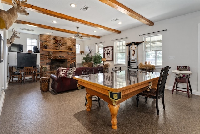 dining space featuring ceiling fan, a fireplace, and beamed ceiling