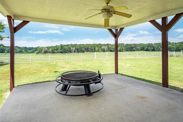 view of patio with ceiling fan, a rural view, and an outdoor fire pit