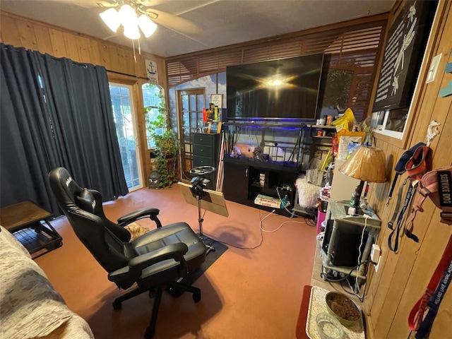 interior space featuring carpet flooring, wooden walls, and ceiling fan