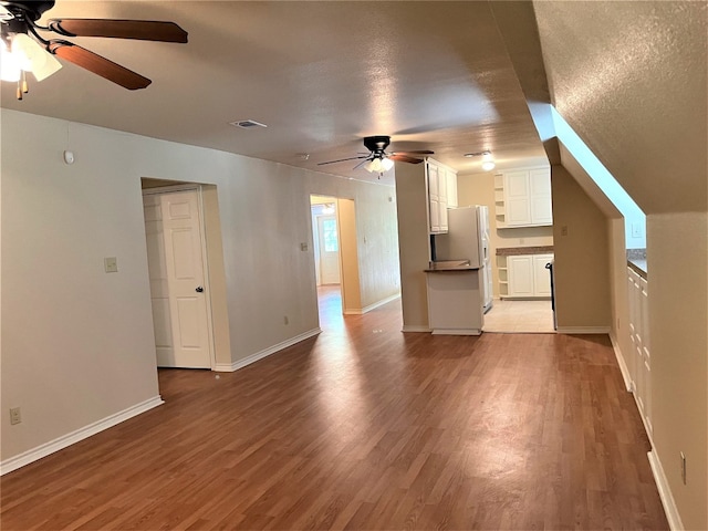 additional living space featuring a textured ceiling, wood-type flooring, and ceiling fan