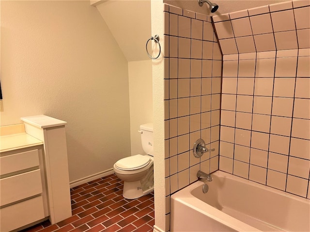 bathroom with tile floors, toilet, tiled shower / bath, and vaulted ceiling