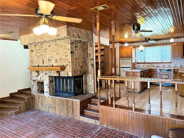 unfurnished living room with ceiling fan, sink, wooden ceiling, beverage cooler, and a stone fireplace