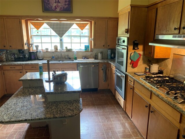 kitchen featuring light stone countertops, backsplash, sink, and stainless steel appliances