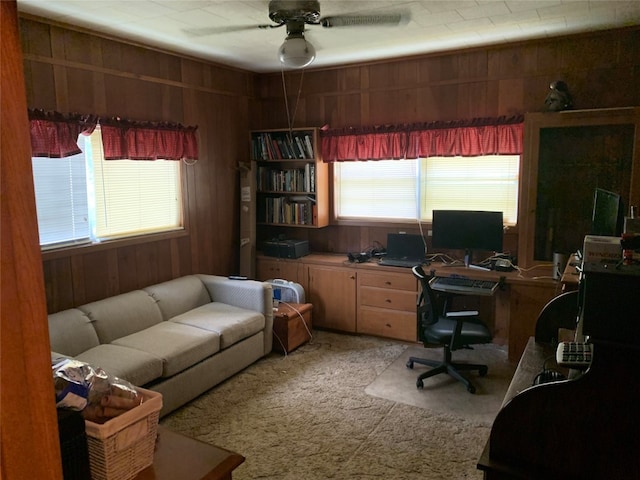 carpeted office with wooden walls and ceiling fan