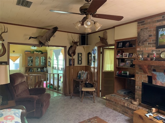 carpeted living room featuring brick wall, ornamental molding, ceiling fan, and a fireplace