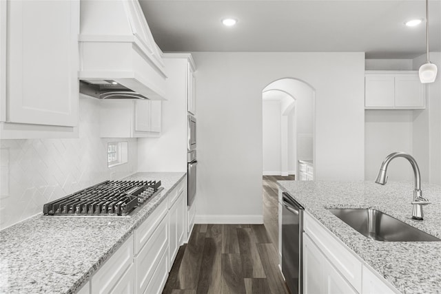 kitchen with appliances with stainless steel finishes, sink, custom range hood, dark hardwood / wood-style flooring, and pendant lighting