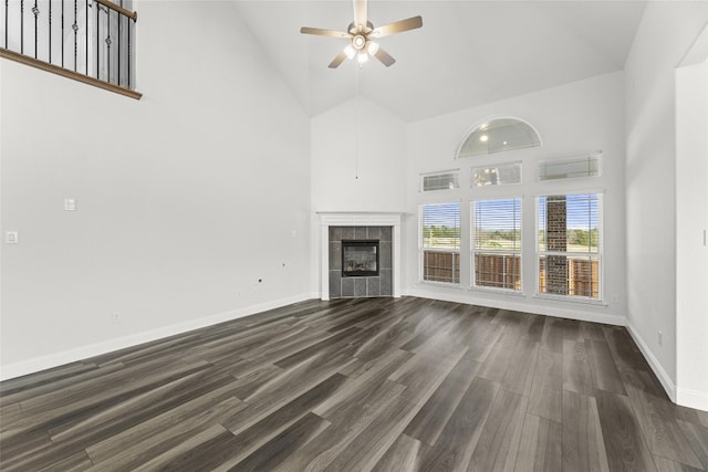 unfurnished living room with a tiled fireplace, high vaulted ceiling, ceiling fan, and dark hardwood / wood-style flooring