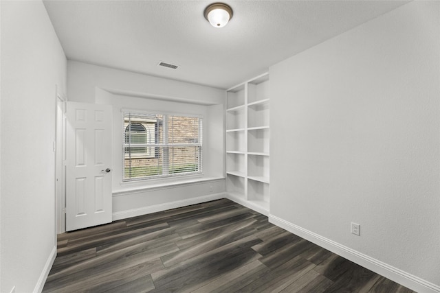 empty room featuring built in features and dark hardwood / wood-style floors