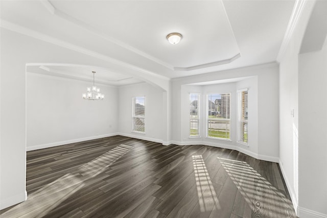 spare room featuring a chandelier, dark hardwood / wood-style floors, a tray ceiling, and crown molding