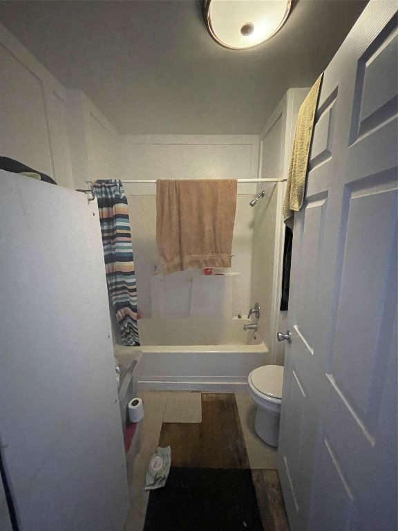 bathroom with toilet, shower / tub combo with curtain, and tile flooring