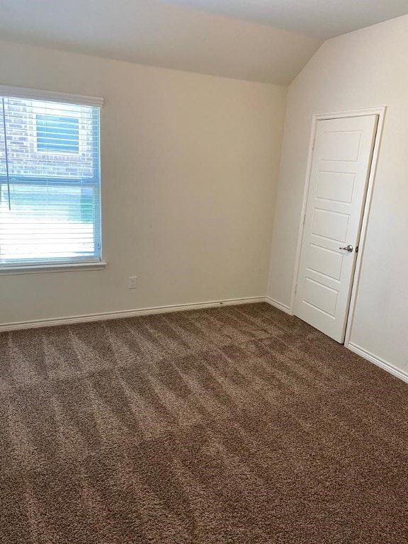 carpeted spare room featuring lofted ceiling