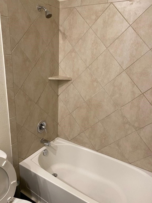 bathroom featuring tiled shower / bath and toilet