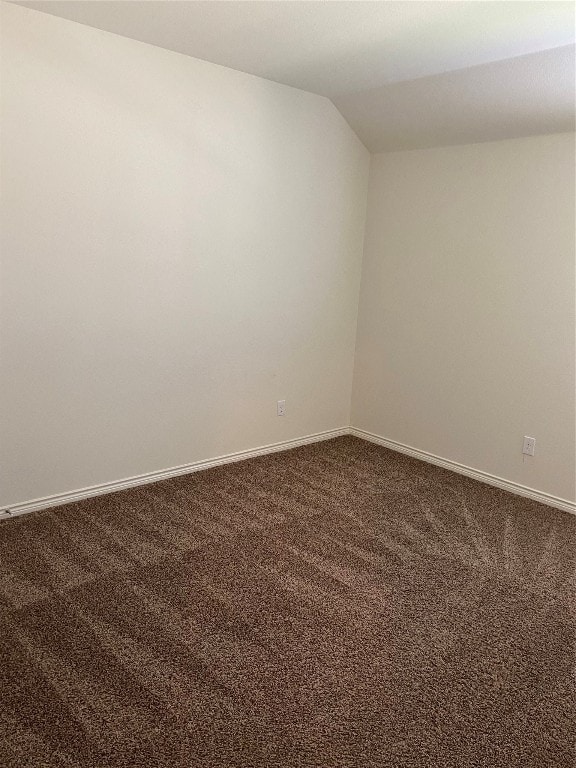 carpeted empty room with vaulted ceiling