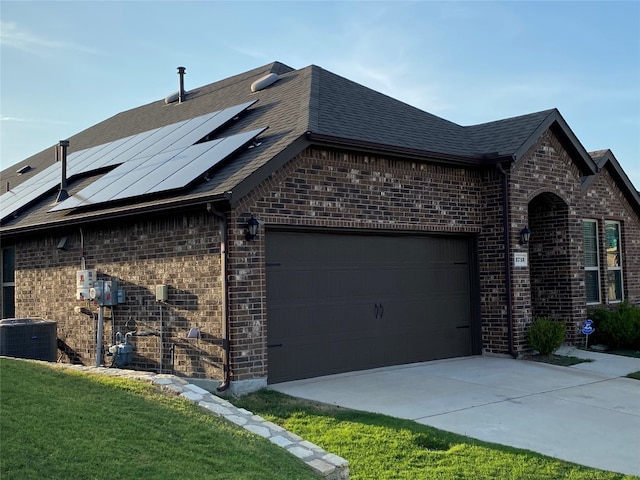 view of home's exterior featuring central AC, solar panels, a yard, and a garage