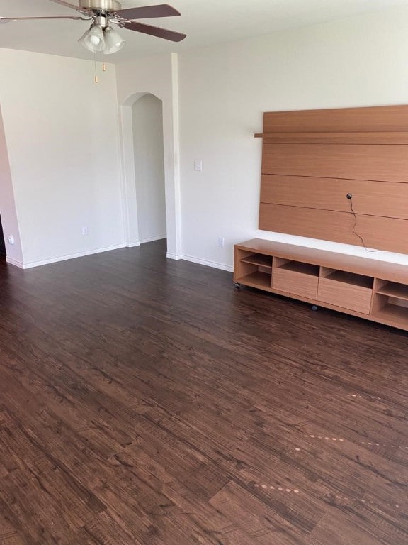 unfurnished living room with ceiling fan and dark wood-type flooring