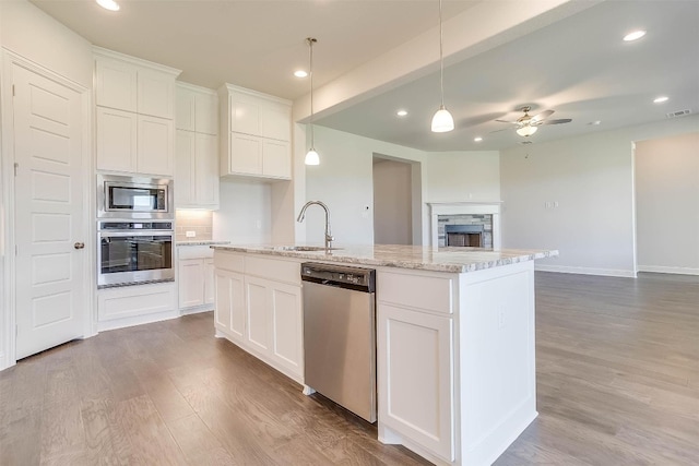 kitchen featuring appliances with stainless steel finishes, white cabinetry, ceiling fan, and light hardwood / wood-style flooring