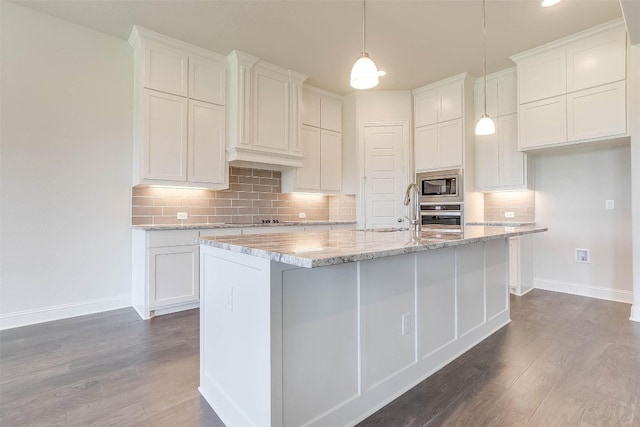 kitchen featuring a kitchen island with sink, backsplash, dark wood-type flooring, and stainless steel appliances