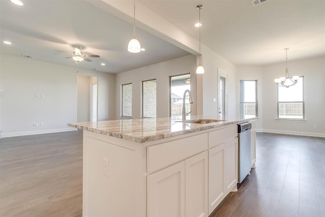 kitchen featuring pendant lighting, ceiling fan with notable chandelier, sink, white cabinetry, and a center island with sink