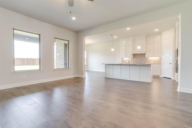 unfurnished living room with sink, ceiling fan, and hardwood / wood-style flooring