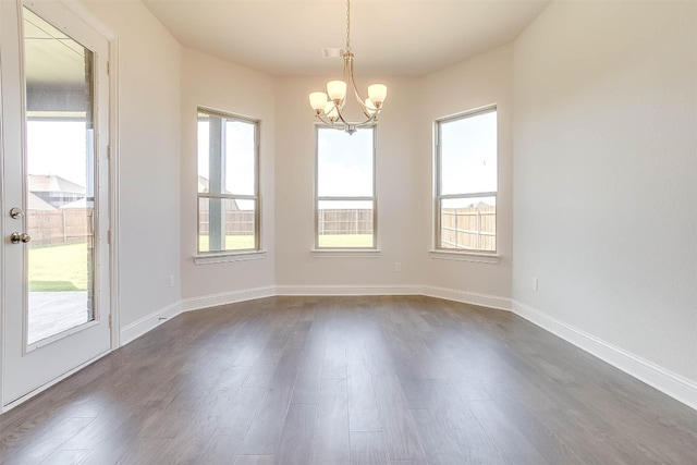 spare room with dark hardwood / wood-style flooring and a chandelier