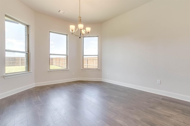 spare room with an inviting chandelier and dark wood-type flooring