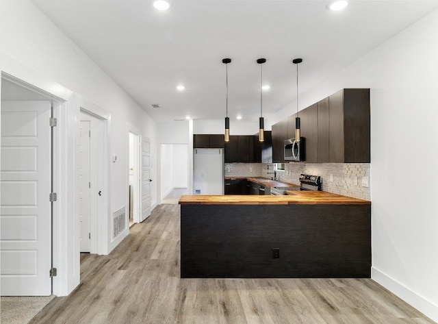 kitchen featuring light hardwood / wood-style floors, tasteful backsplash, stainless steel appliances, and decorative light fixtures