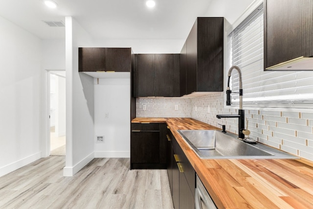 kitchen featuring backsplash, light hardwood / wood-style floors, butcher block counters, and sink