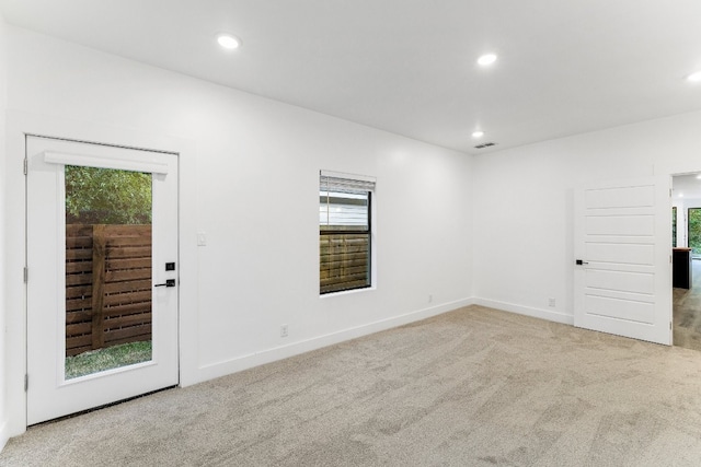 unfurnished room with light colored carpet and a wealth of natural light