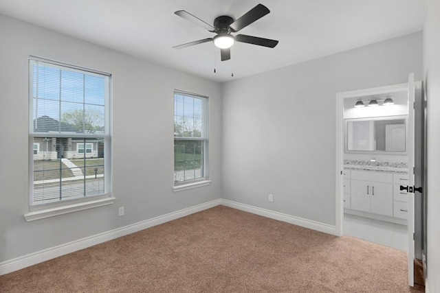 carpeted spare room featuring a healthy amount of sunlight, ceiling fan, and sink