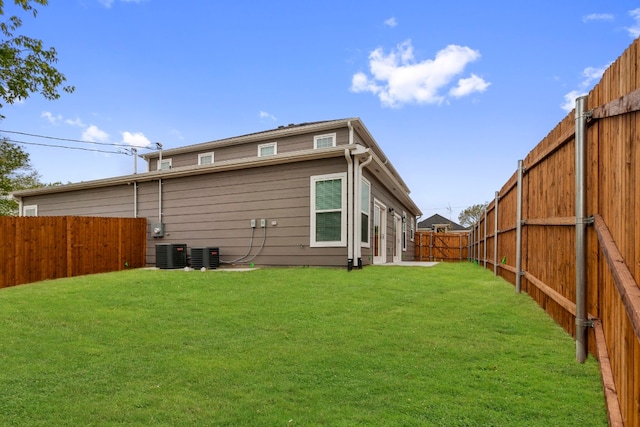 rear view of property with a yard and central AC