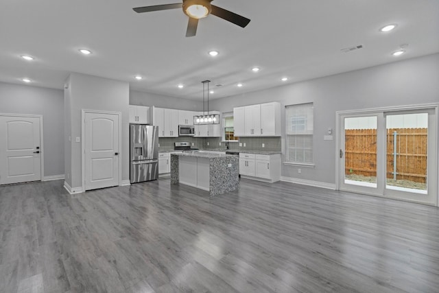 kitchen featuring dark hardwood / wood-style floors, a kitchen island, decorative light fixtures, and appliances with stainless steel finishes