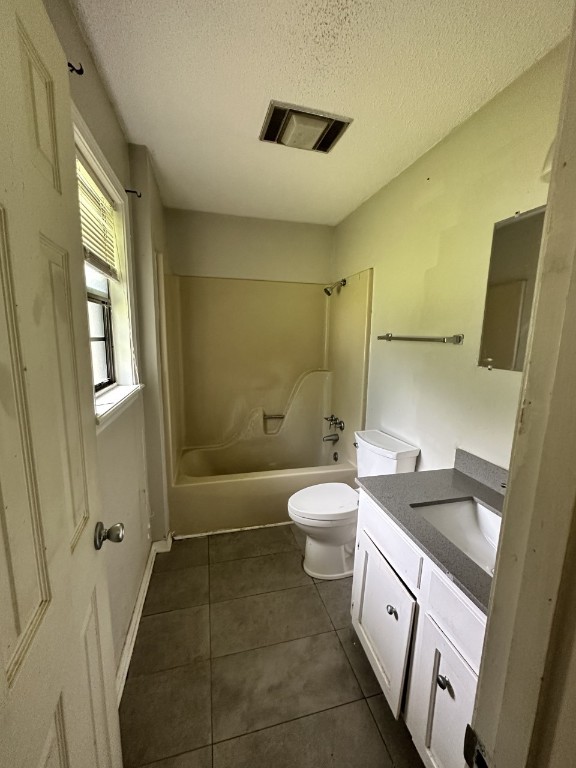 full bathroom featuring tile floors, bathing tub / shower combination, a textured ceiling, toilet, and vanity