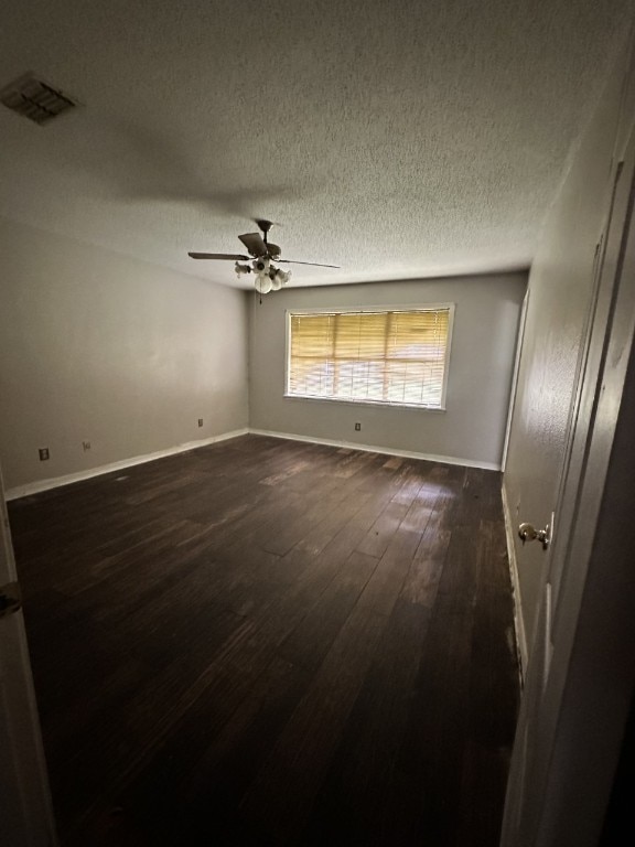 spare room featuring dark hardwood / wood-style flooring, a textured ceiling, and ceiling fan