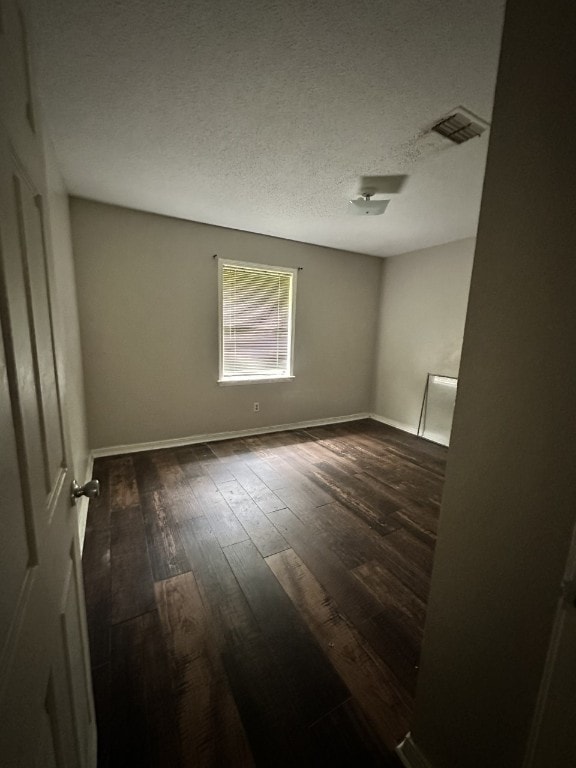 unfurnished room with a textured ceiling and dark wood-type flooring