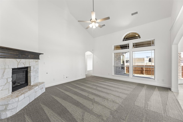 unfurnished living room featuring a high ceiling, light carpet, ceiling fan, and a fireplace