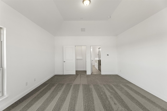 unfurnished bedroom featuring dark carpet, ensuite bathroom, and a closet