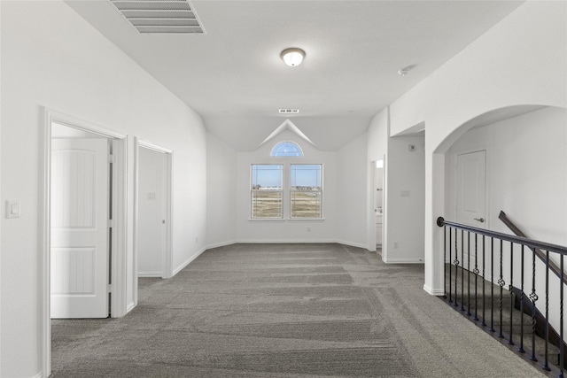 hall with lofted ceiling and dark colored carpet