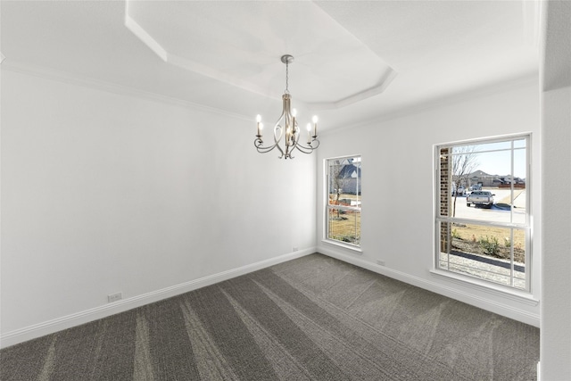 spare room featuring plenty of natural light, a chandelier, a raised ceiling, and dark colored carpet