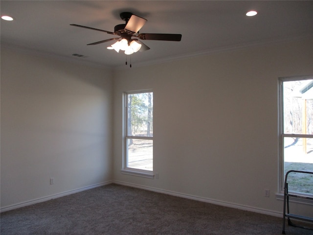 empty room with dark colored carpet, ceiling fan, and a healthy amount of sunlight