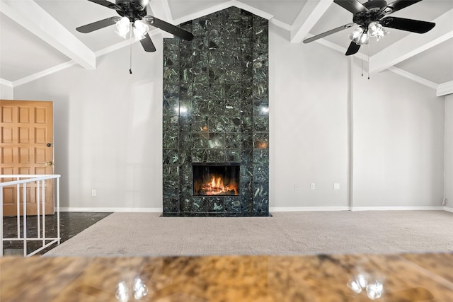 unfurnished living room featuring carpet, a premium fireplace, ceiling fan, and vaulted ceiling with beams