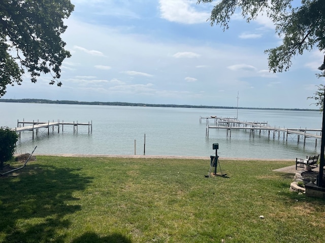 view of dock with a water view and a lawn