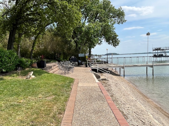 exterior space with a boat dock, a water view, and a lawn