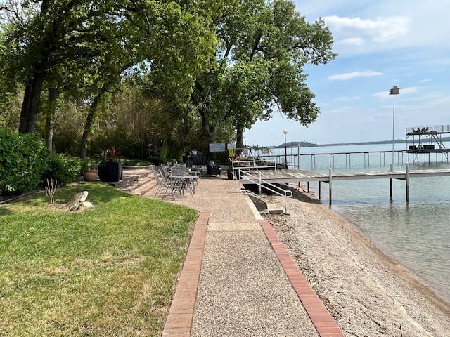 view of dock with a yard and a water view