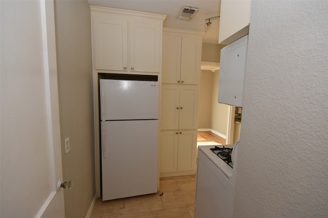 kitchen with white appliances, light wood-type flooring, and white cabinetry