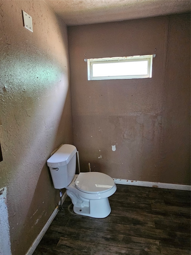 bathroom featuring wood-type flooring, toilet, and a textured ceiling