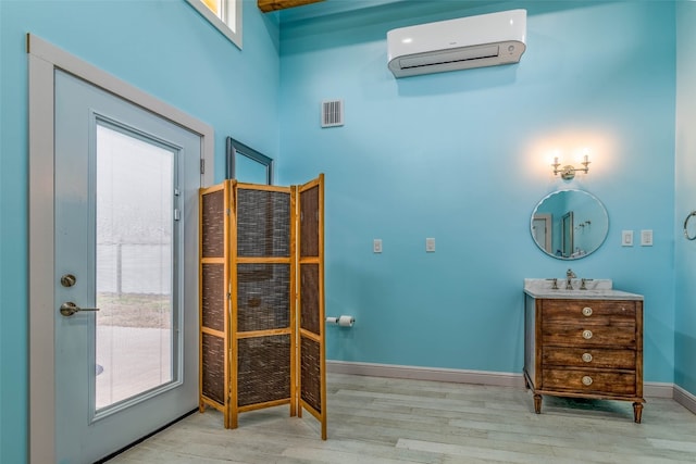 interior space featuring a towering ceiling, a wealth of natural light, light wood-type flooring, and an AC wall unit