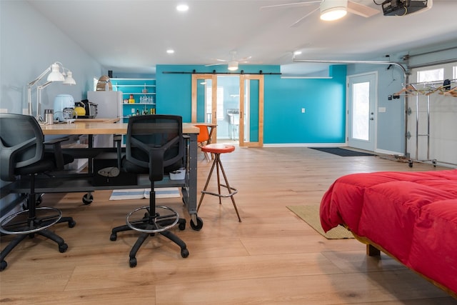 bedroom featuring a barn door, light hardwood / wood-style flooring, and access to outside