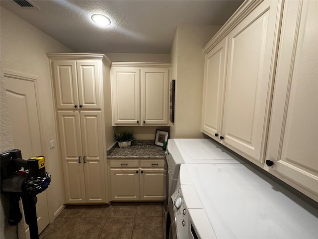 laundry room featuring dark tile flooring, cabinets, and separate washer and dryer