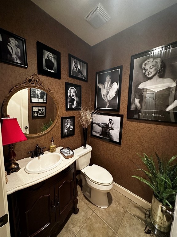 bathroom with toilet, large vanity, and tile floors